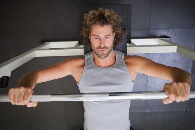 Photo muscular man lifting barbell in gym