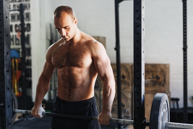 muscular man lifting dumbbell in gym