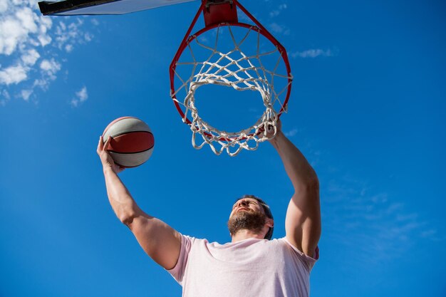 Muscular man player throw basketball ball through basket male basketball