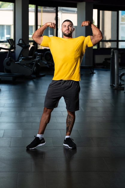 黄色のTシャツでポーズをとる筋肉の男