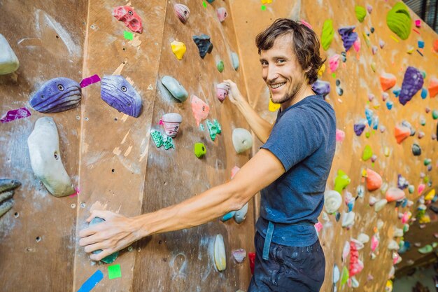 Muscular man practicing rockclimbing on a rock wall indoors
