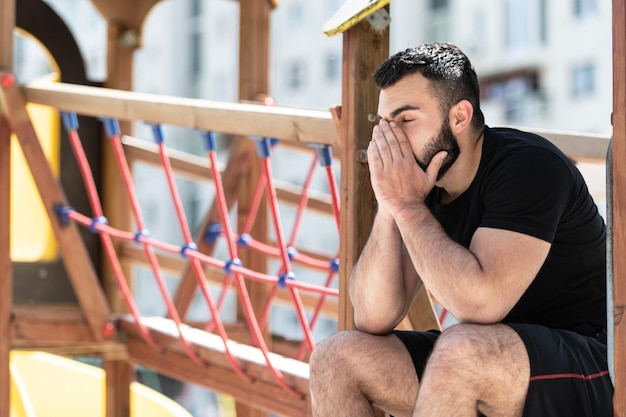 Photo muscular man resting after exercising outdoors on playground