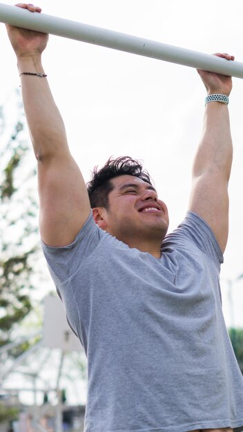 Muscular man smiling performing pushups, he is in a park.