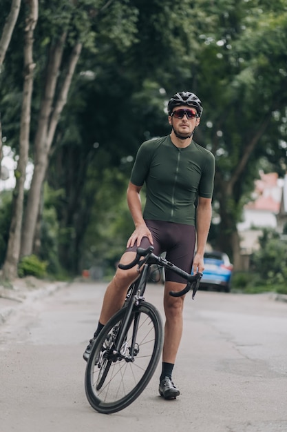 Muscular man in sport clothes sitting on bike on city street