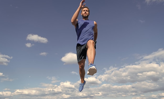 Velocista uomo muscoloso che corre in abbigliamento sportivo all'aperto sulla maratona di sfondo cielo