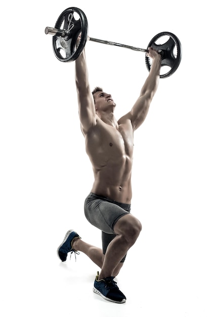 Muscular man standing on knee, holding barbell over his head