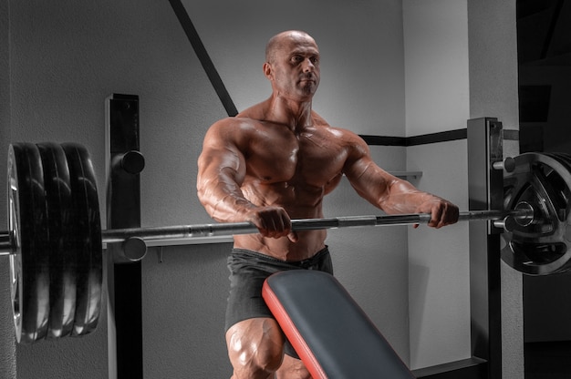 Muscular man stands near the barbell. Bodybuilding concept.