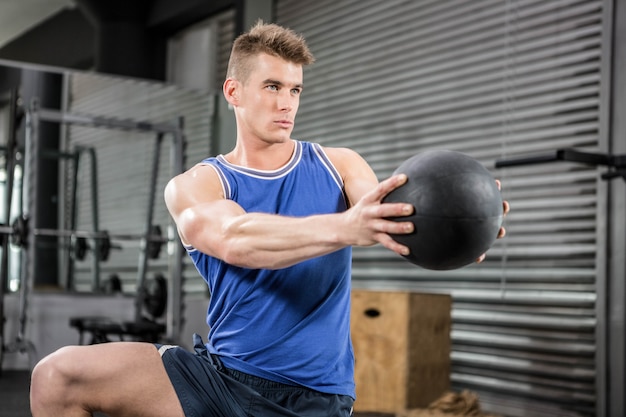 Мускулистый мужчина тренируется с мячом в тренажерном зале crossfit