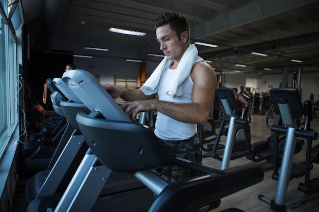 Photo muscular man using exercise machine in gym