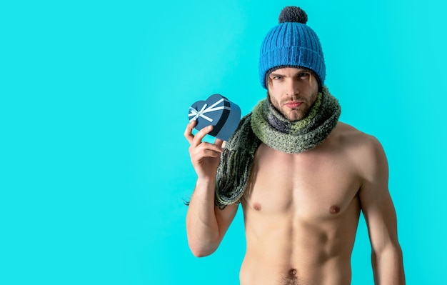 Muscular man valentines present isolated on blue copy space man in knitwear hold present