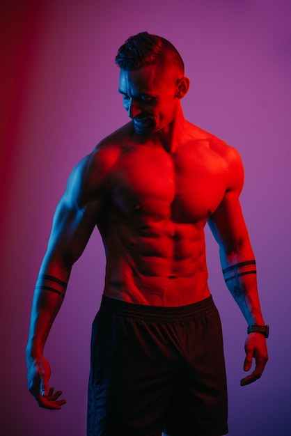 A muscular man with a beard is relaxing under the blue and red light