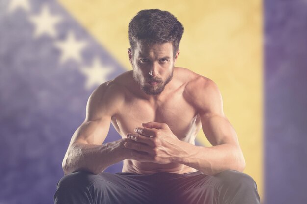 Muscular man with Bosnia and Herzegovina Flag behind