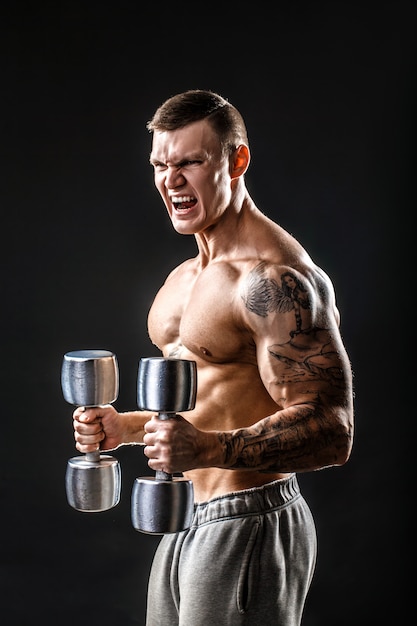 Muscular man with dumbbell. side view. black background