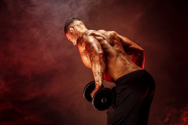 Photo muscular man with dumbbells doing exercises  photo of strong male with naked torso isolated on white scene  strength and motivation  back view