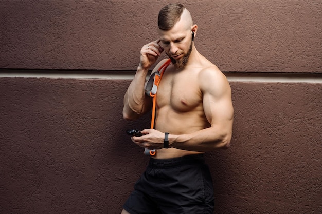 Muscular man with naked torso with stratching rubber posing outdoors