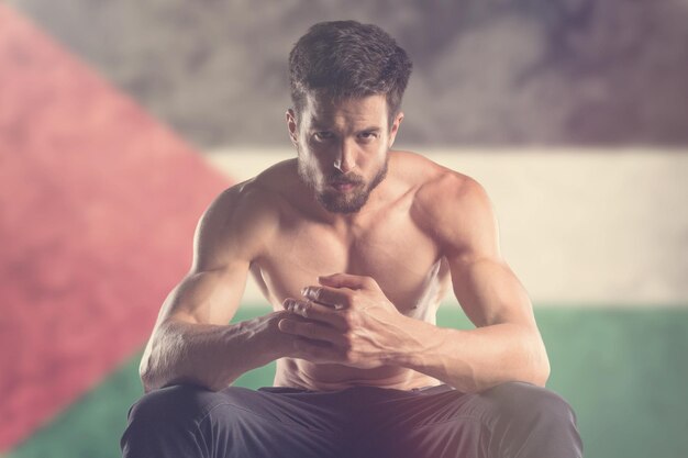 Muscular man with Palestine flag behind