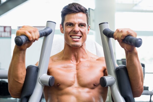 Muscular man working on fitness machine at the gym