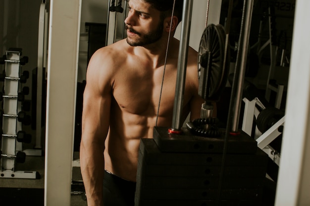 Muscular man working out in gym doing triceps exercises