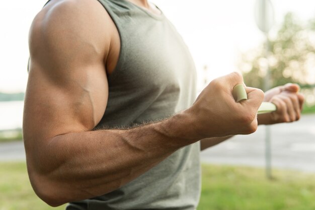 屋外で抵抗ゴムバンドでトレーニング中の筋肉質の男。