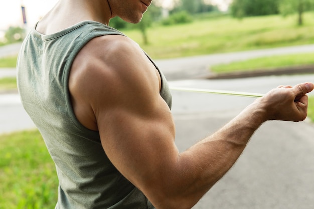 Muscular man during  workout with a resistance rubber bands outdoors.