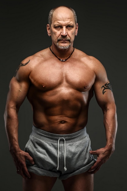 Muscular middle age man posing in studio. Isolated on grey