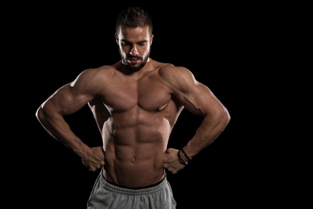 Muscular Model Flexing Muscles On Black Background