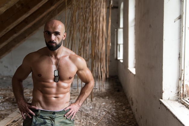 Photo muscular model flexing muscles in shelter