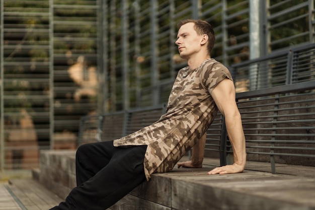 Muscular model man in khaki tshirt on backgroundof outdoor gym