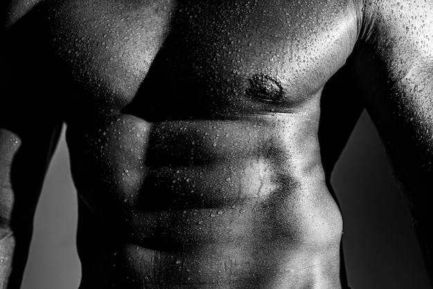 Фото Мускулистый мужчина-модель на темном фоне мускулистый гей-сексуальный с шестью пакетами пресса в студии