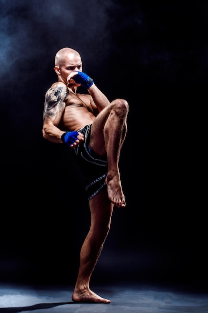 Photo muscular muay thai fighter punching in darkness