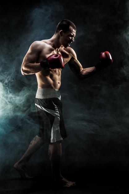 Muscular muay thai fighter punching in smoke