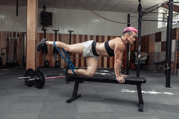 Muscular powerful woman works out with fitness rubber bands in the gym. Healthy lifestyle concept