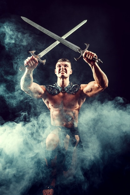 Muscular shirtless man posing fiercely with swords