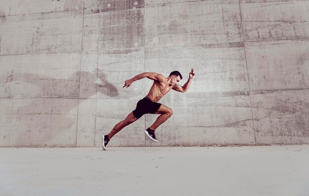 写真 外で走っている筋肉のシャツのない男