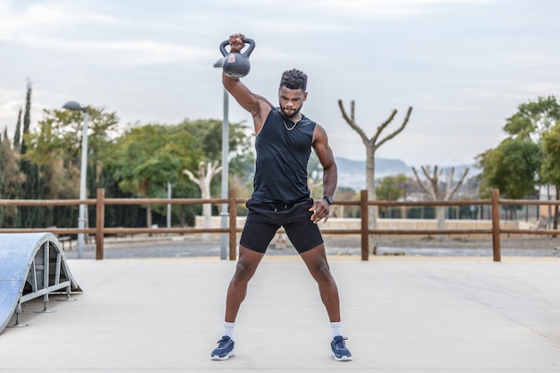 Muscular sportsman exercising with kettlebell in park