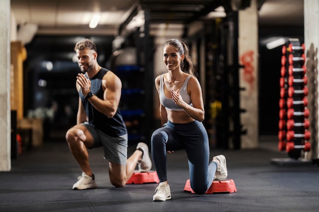 muscular sporty friends doing lunges in a gym