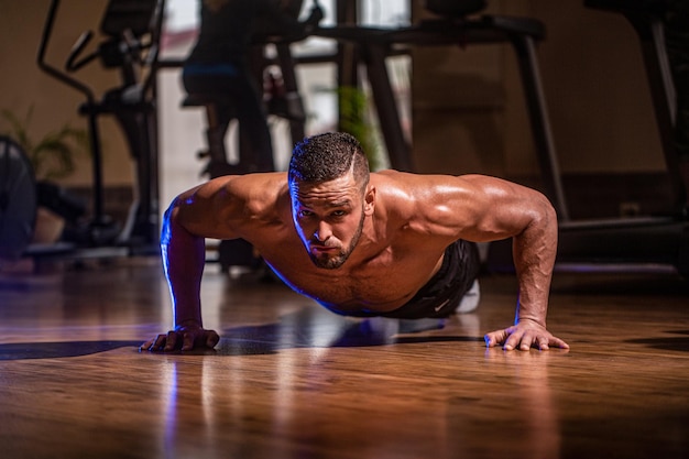 Muscular and strong guy exercising Muscular male doing pushups Slim man doing some push ups a the gym Man doing pushups Muscular man doing pushups on one hand against gym background Sport