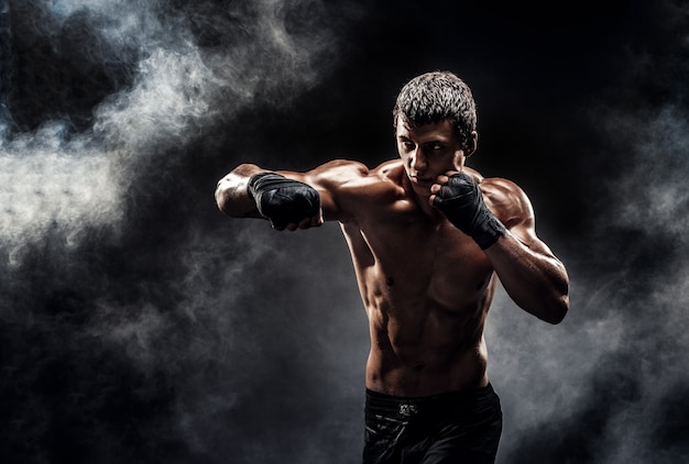 Muscular topless fighter in boxing gloves