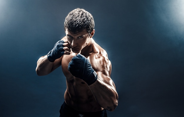 Muscular topless fighter in boxing gloves