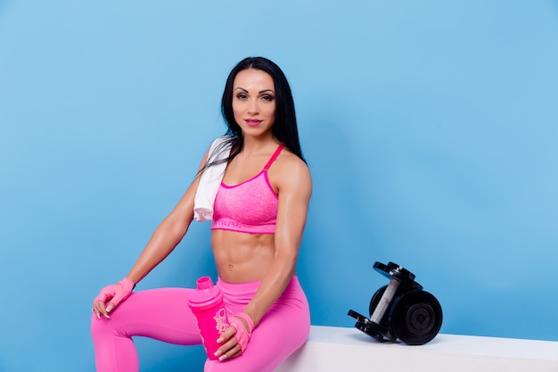 Muscular woman having a rest and holding bottle