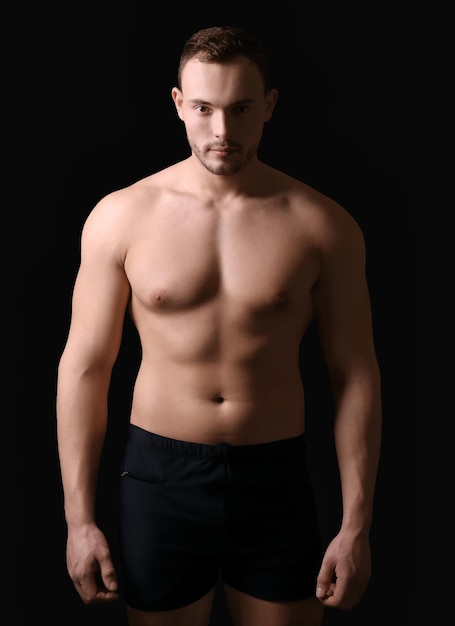 Photo muscular young bodybuilder on dark background