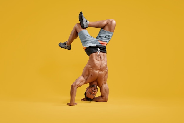 Muscular young bodybuilder performing handstand stunt