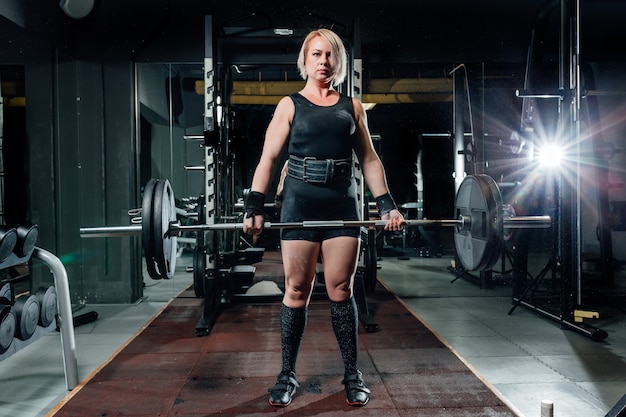 Muscular young fitness woman lifting a weight crossfit in the gym.