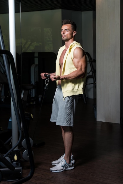 Muscular Young Man Bodybuilder Doing Heavy Weight Exercise For Biceps On Cable Machine