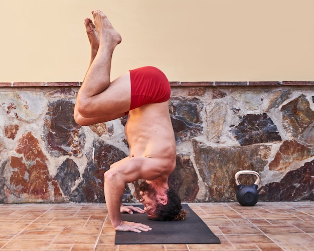 Muscular young man doing handstand at home. Home workout concept and healthy living.