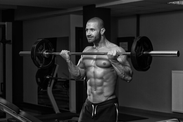 Muscular Young Man Doing Heavy Weight Exercise For Biceps In Gym