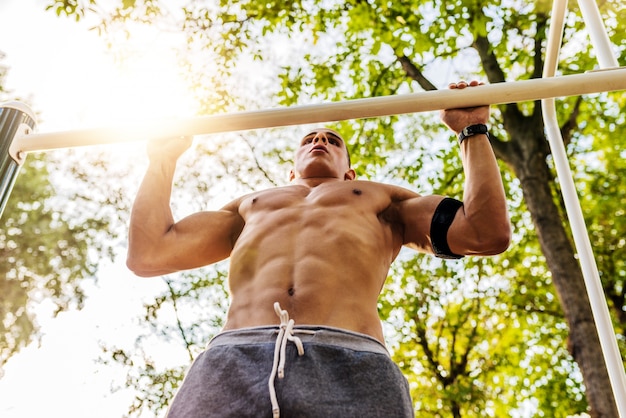 Muscular young man during his workout on the street. 