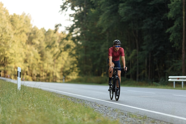 녹색 숲 사이에서 자전거에 스포츠 활동을하는 스포츠 의류 및 보호 헬멧에 근육 질의 젊은 남자