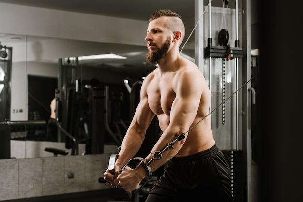 Фото Мускулистый молодой человек, работающий в спортзале, делает упражнения на трицепс
