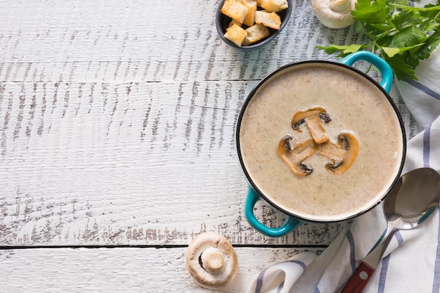 Mushroom champignon cream soup on white wooden board View from above Space for text